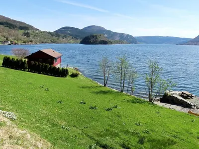 a house on a grass field next to a body of water at Holiday Home Nanna by Interhome in Hyllestad