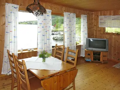 a dining room with a table and a television at Holiday Home Nanna by Interhome in Hyllestad