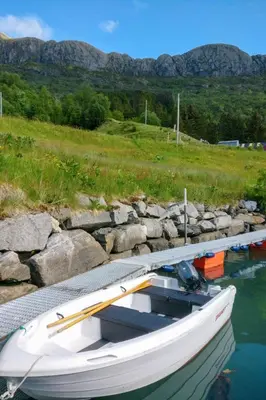 a white boat tied to a dock in the water at Holiday Home Idun by Interhome in Hyllestad