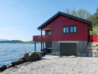 a red house on the shore of a body of water at Holiday Home Idun by Interhome in Hyllestad