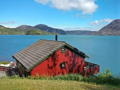 a red house sitting on the side of a lake at Holiday Home Idun by Interhome in Hyllestad