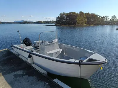 a white boat docked at a dock on a lake at Holiday Home Strøneneset by Interhome in Hagavik