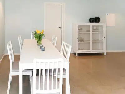 a white dining room table with white chairs and a vase of flowers at Apartment Huglavika by Interhome in Nordhuglo