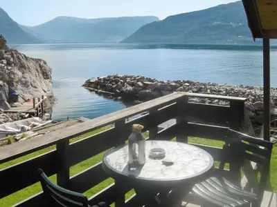 a table with a vase on it next to a lake at Chalet Hardangerrorbu by Interhome in Tjoflot
