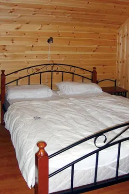 a bed in a room with a wooden wall at Chalet Hardangerrorbu by Interhome in Tjoflot