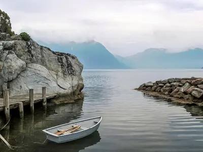 a small boat in the water next to a dock at Chalet Eiknes by Interhome in Tjoflot
