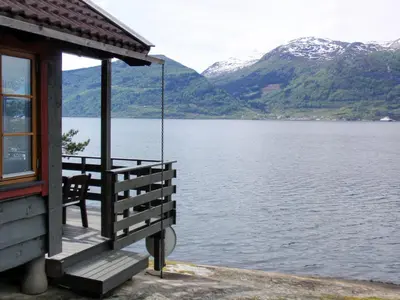a house with a porch swing overlooking a lake at Chalet Eiknes by Interhome in Tjoflot