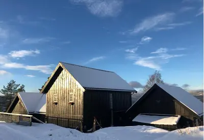 a wooden barn with snow on the roof at Villa Fjara sleeps 22 in 6 bedrooms in Ulven