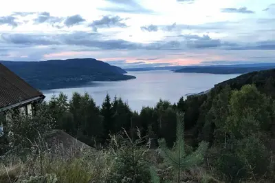 a view of a lake from a hill with a house at Villa Fjara sleeps 22 in 6 bedrooms in Ulven