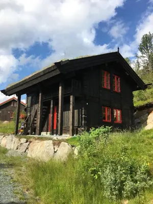 a black house with red windows on a hill at Nilsrud 30 Feriehus in Åmotsdal