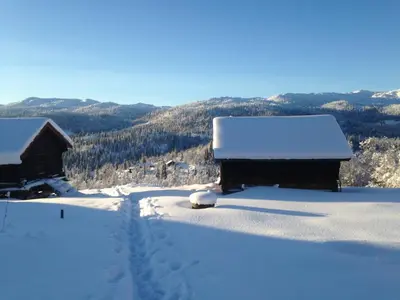 a snow covered yard with a house and a mountain at Nilsrud 30 Feriehus in Åmotsdal