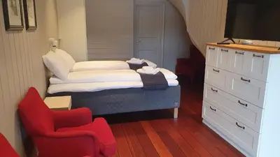 a small bedroom with a bed and a chair at Villa Oleanna in Lysekloster