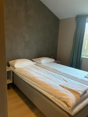 a bed with white sheets and pillows next to a window at Nygårdsgaten apartments in Bergen