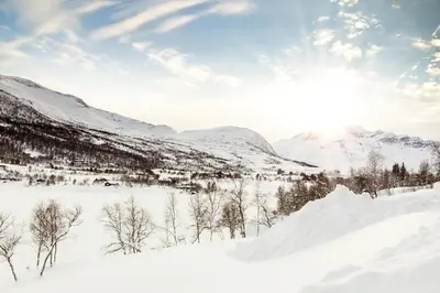 a snow covered field with mountains in the background at Røde Kors ground floor in Brunstad