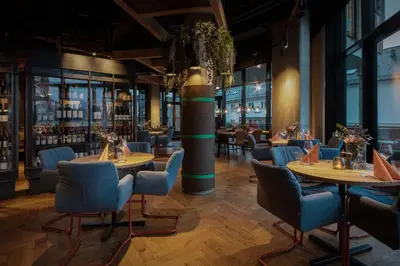 a restaurant with round tables and blue chairs at Scandic Voss in Vossevangen