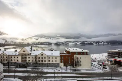 a city with snow covered buildings and a body of water at Scandic Voss in Vossevangen