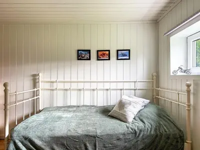 a bed in a bedroom with three pictures on the wall at Holiday Home Rødehuset by Interhome in Gjelland