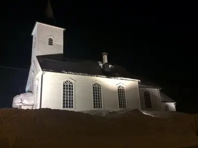 a white church at night with snow around it at Voss- Oppheim suite private cozy cabin in Vossestrand