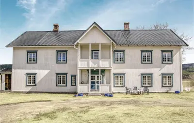 a large white house with black windows and chairs at Beautiful Home In Tynset With Kitchen in Tynset