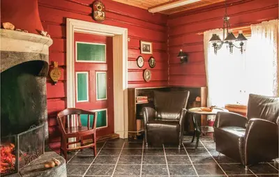 a living room with red walls and chairs and a fireplace at Beautiful Home In Tynset With Kitchen in Tynset