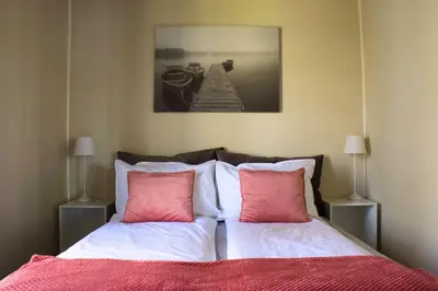 a bedroom with a bed with pink and white pillows at Eidsvåg Fjordhotell in Eidsvåg