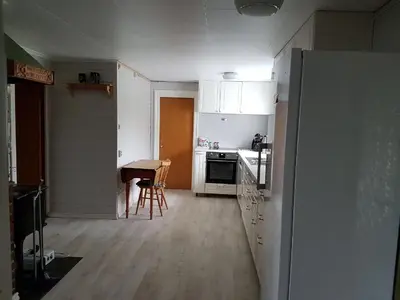 a kitchen with white cabinets and a table in it at Presthus Gård in Ølve
