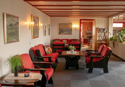 a waiting room with red chairs and tables at Rondane Haukliseter Fjellhotell in Høvringen