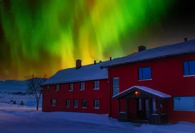a red building with the aurora in the sky at Rondane Haukliseter Fjellhotell in Høvringen