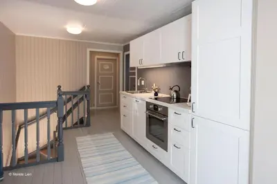a kitchen with white cabinets and a sink and a stove at Kirkvollen pilegrimsgård in Tydal