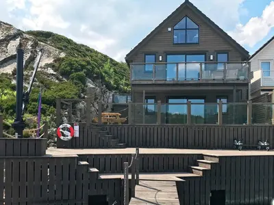 a wooden house with glass doors and stairs at 8 person holiday home in Urangsvåg in Ervik