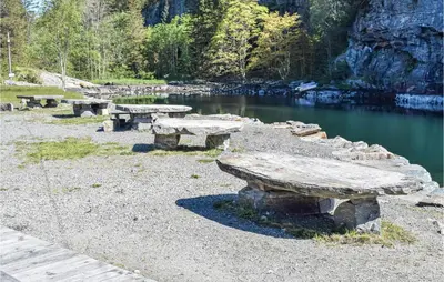a group of stone benches sitting next to a lake at 2 Bedroom Cozy Home In Hauglandshella in Kolavåg