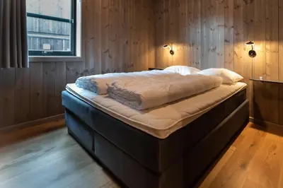 a large bed in a room with wooden walls at Trysiltunet 16b in Trysil