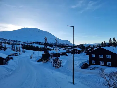 a snow covered village with a street light and a mountain at Gaustatoppen Apartment in Rjukan