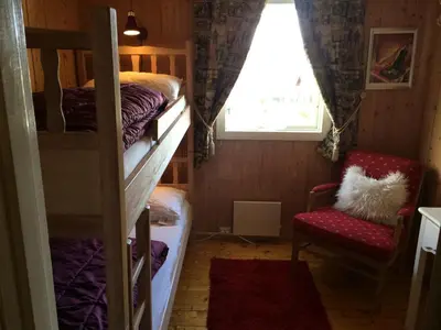 a bedroom with bunk beds and a chair and a window at Kjøniksbu - 3 bedroom cabin in Ål