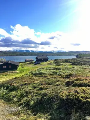 a field with houses and a body of water at Veslehytta - cabin 1050 moh via amazing view and ambiance in Ål