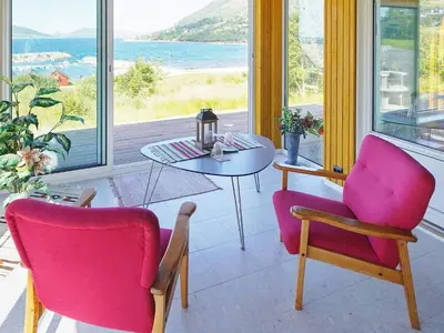 a room with two chairs and a table with a view of the ocean at 8 person holiday home in Åram in Sandvik