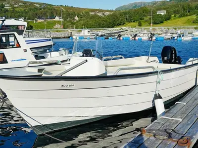 a white boat is docked at a dock at 8 person holiday home in Åram in Sandvik