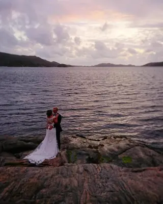 a bride and groom standing on the rocks by the water at Skjerjehamn in Ånneland