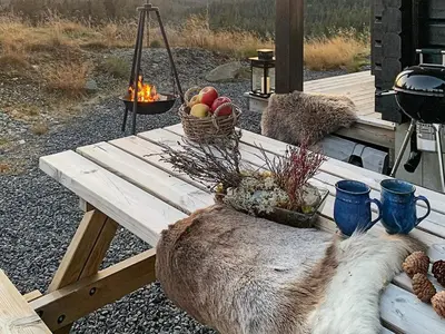 a wooden picnic table with a basket of fruit and a grill at 6 person holiday home in Svingvoll in Svingvoll