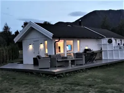 a house with a deck with chairs and a table at feriehus ved sjøen in Tomrefjord