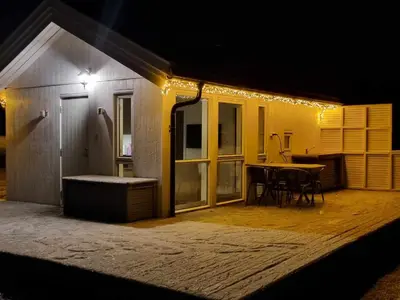 a house with a patio with a table and lights at feriehus ved sjøen in Tomrefjord
