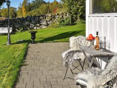 a patio with a table and chairs with wine glasses at Family Oasis with Lake View-By Traum in Ålesund