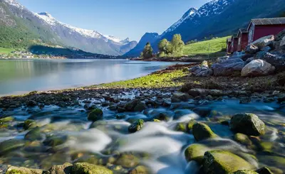 a river with rocks and mountains in the background at Nesset Fjordcamping in Olden