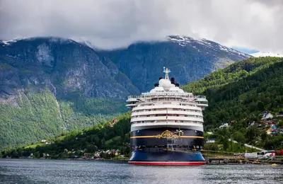 a cruise ship in the water in front of a mountain at Nesset Fjordcamping in Olden