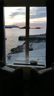 a view of the water from a window with two chairs at Sveggvika Guesthouse in Averoy