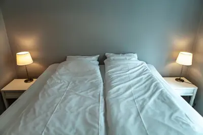 two white beds in a room with two lamps at Forenom Serviced Apartments Bergen City in Bergen
