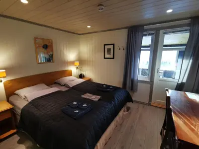 a bedroom with a bed and a table and windows at Eikre Fjellgård in Hemsedal