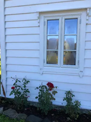 a window on the side of a white house at Eidegrend Boutique Hotel in Eikelandsosen
