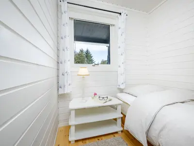 a white bedroom with a bed and a window at Holiday Home Sjøbuvågen by Interhome in Korssund