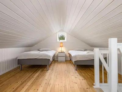 two beds in a white attic bedroom with wood floors at Holiday Home Sjøbuvågen by Interhome in Korssund